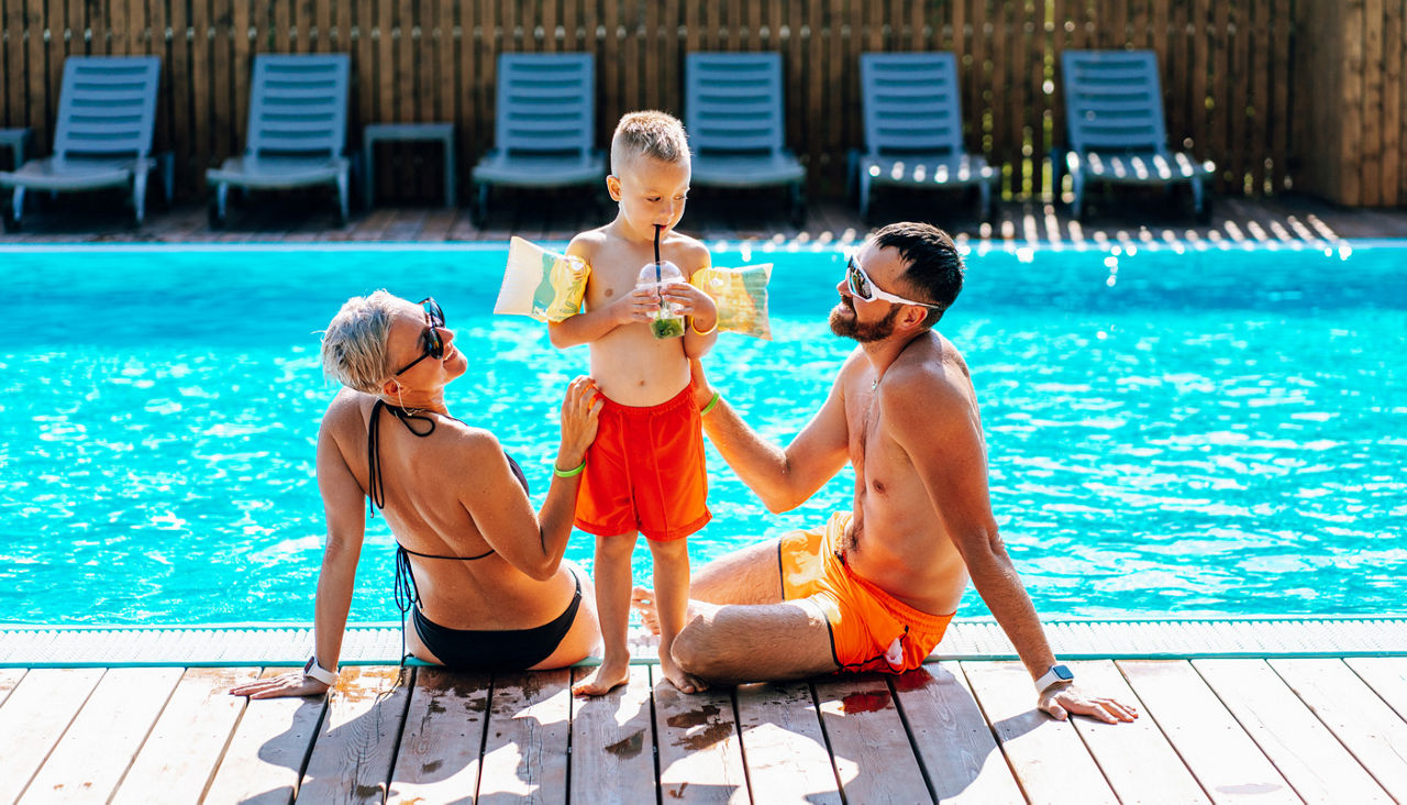 Family enjoying sunny day by swimming pool