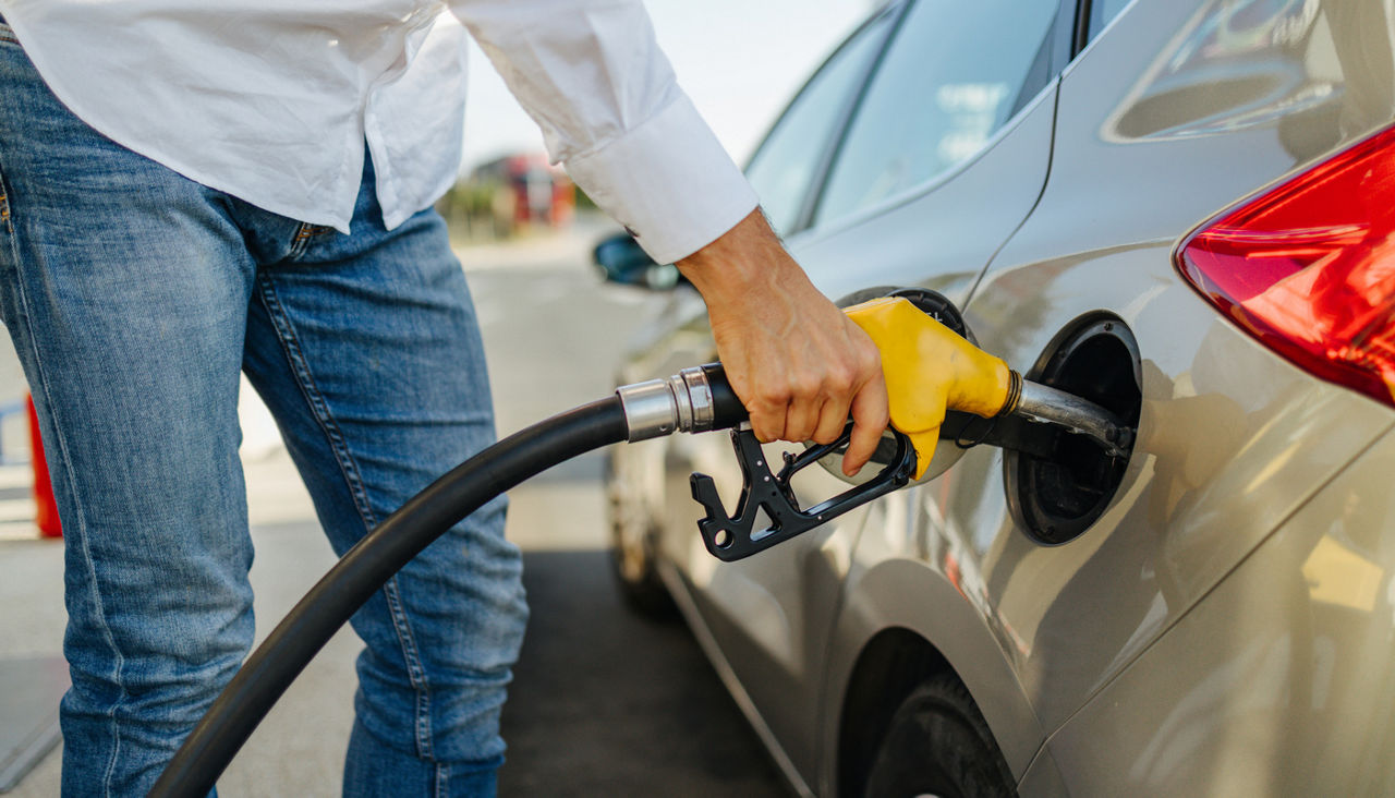 Man pumping gas at a station into a sedan