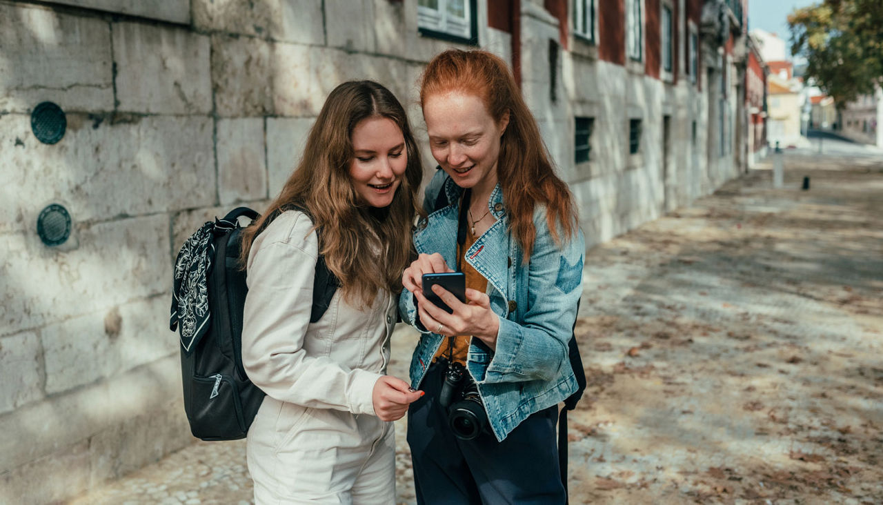 Two women use their smartphone to navigate while exploring the city