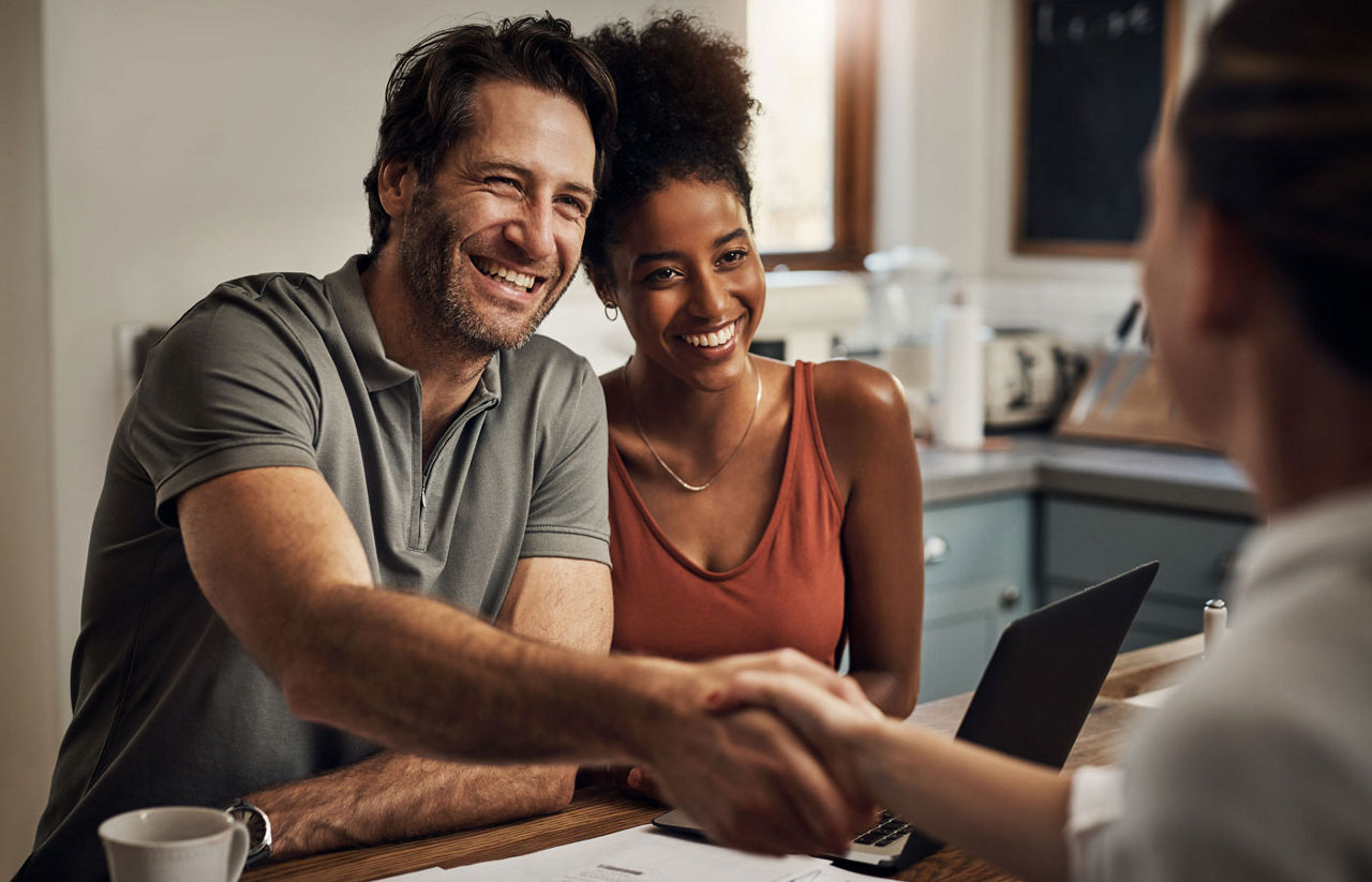 Couple shaking hands with a financial advisor during a consultation at home