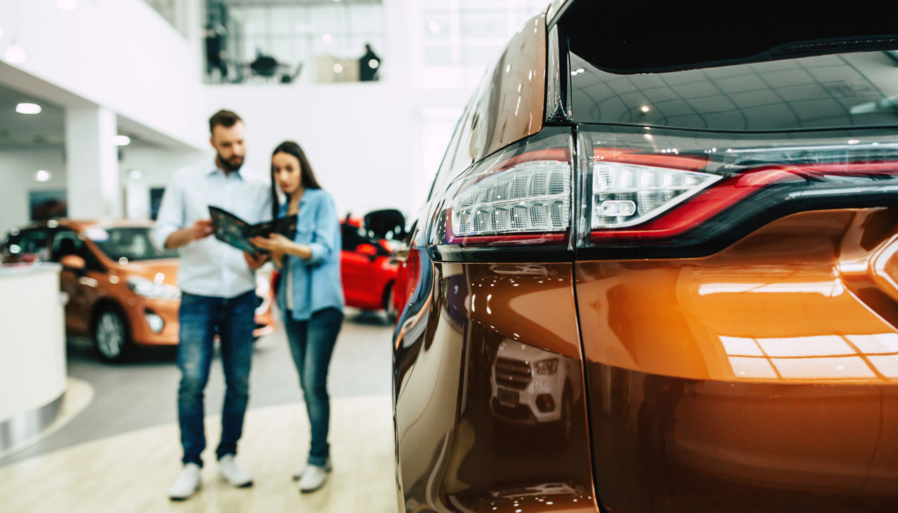 Young couple buying a new car in dealership