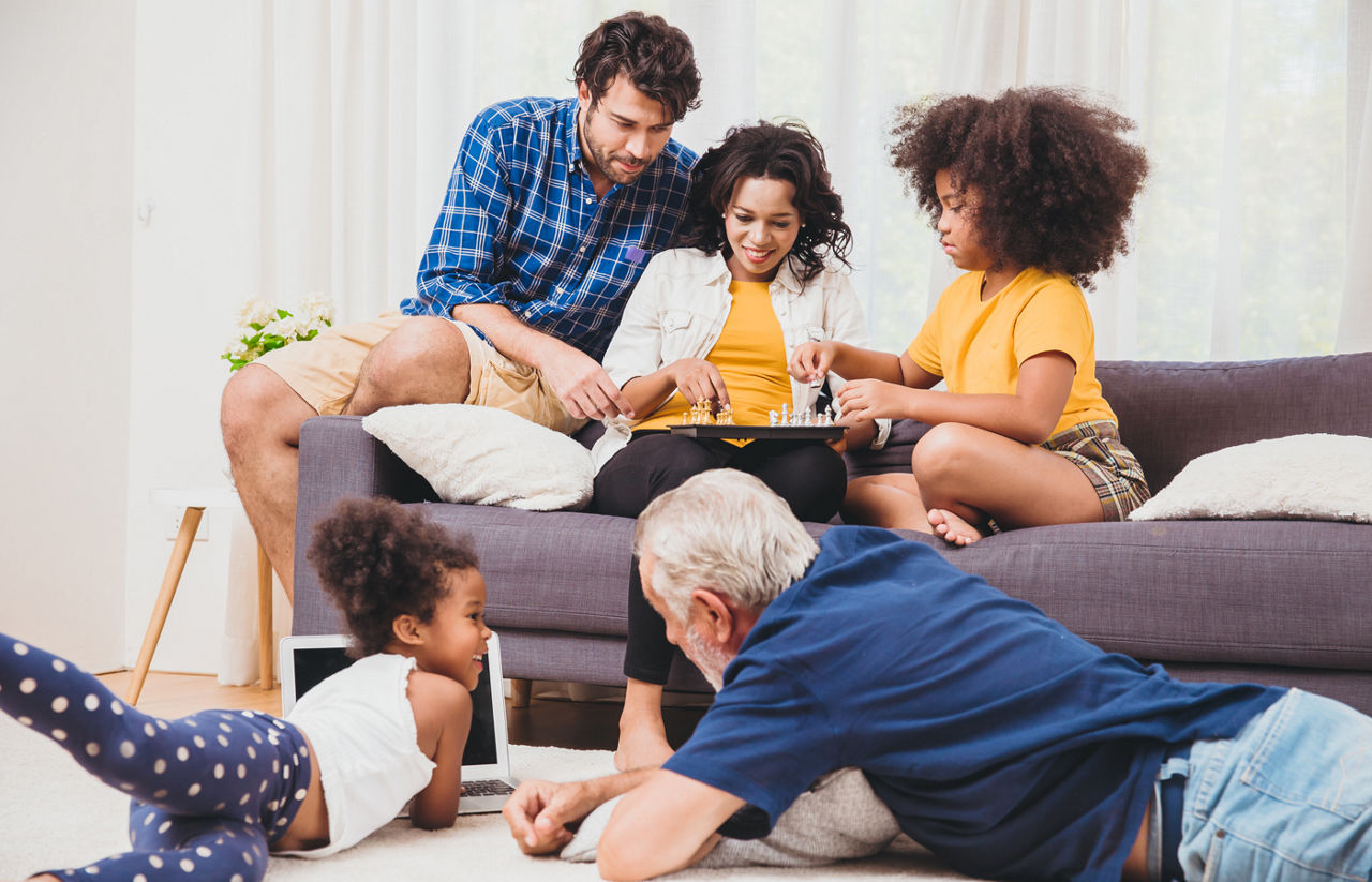 Multigeneration family enjoying playtime in living room with daughters and grandfather