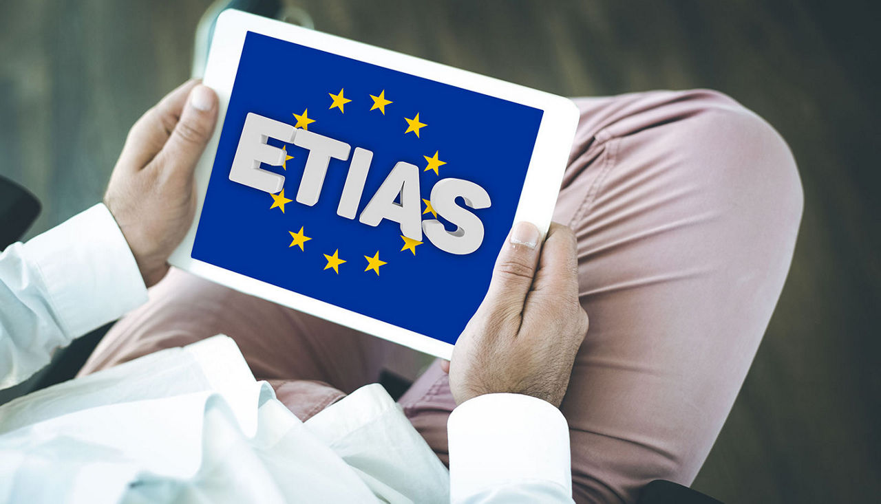 Man holding a tablet that mentions ETIAS