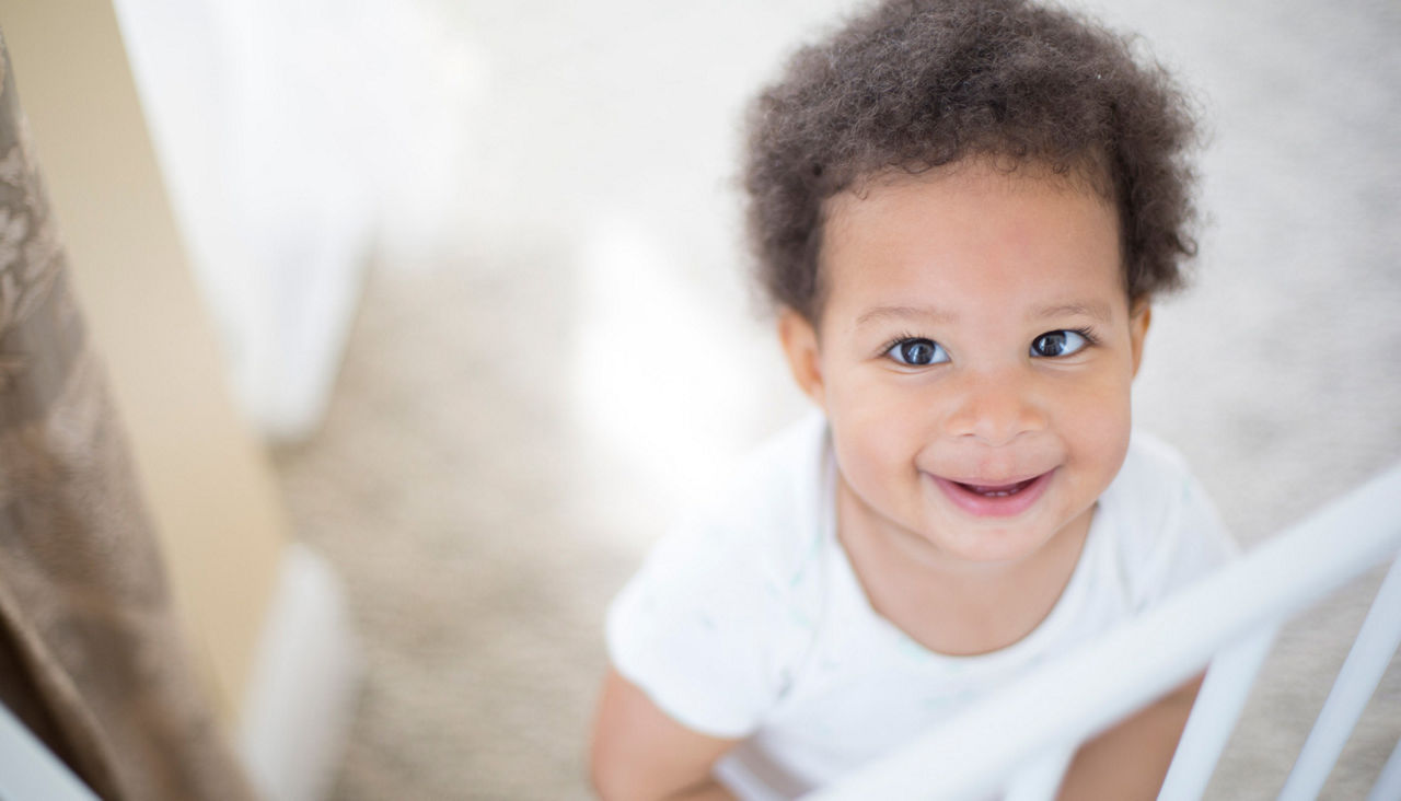 14 month old girl smiling in her crib