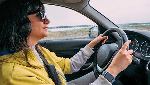 Woman driving modern car on road trip in rainy weather