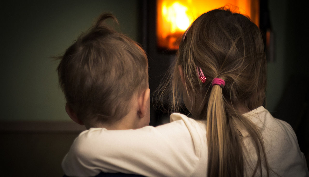 siblings hugging in front of fireplace