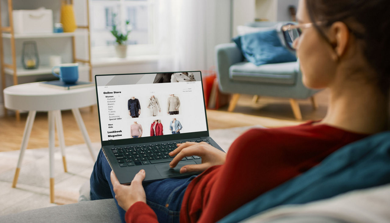 Young Woman at Home Using Laptop Computer for Browsing Through Online Retail Shopping Site
