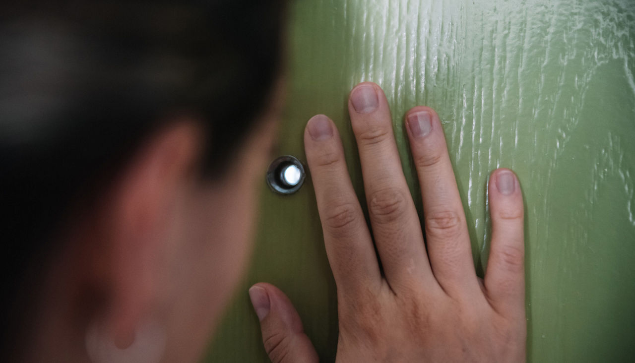 Woman looking through a door viewfinder