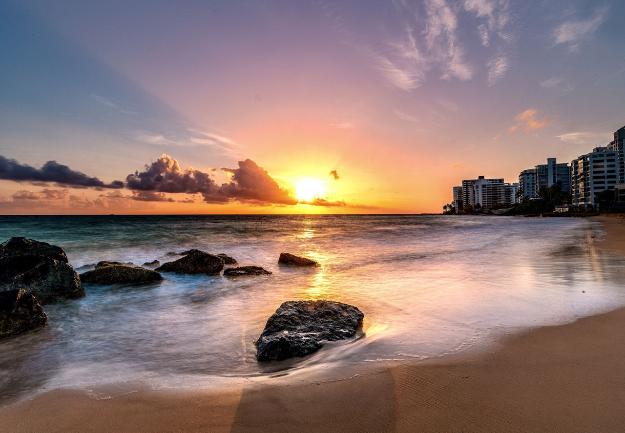 A beach in Puerto Rico at sunset with a row of hotels in the background.