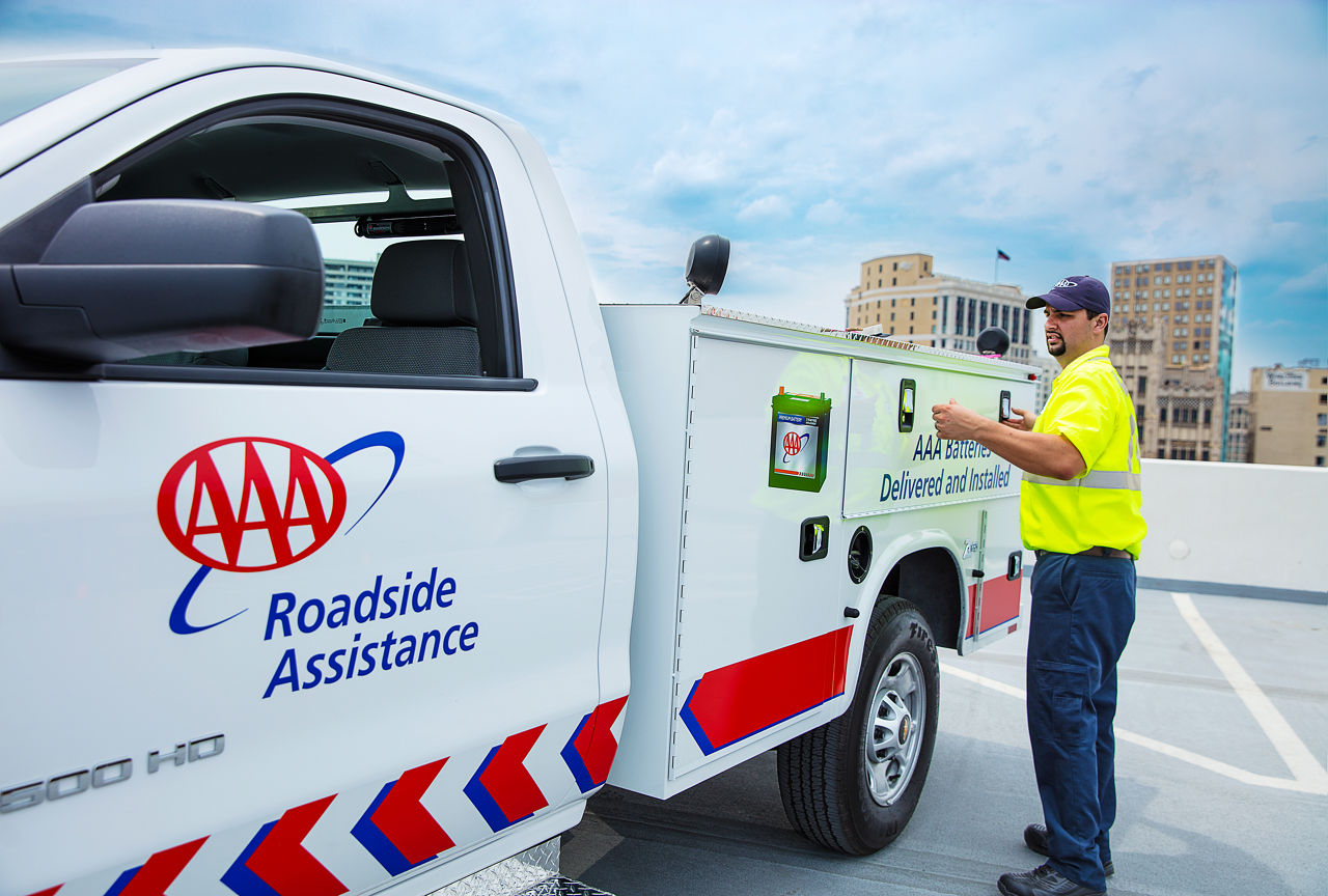 A AAA service man standing next to a AAA roadside assistance truck