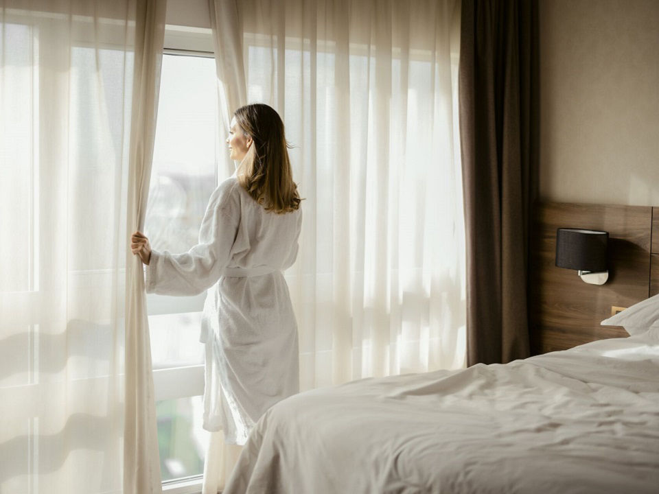 luxury AAA hotel with woman in bathrobe looking out the window