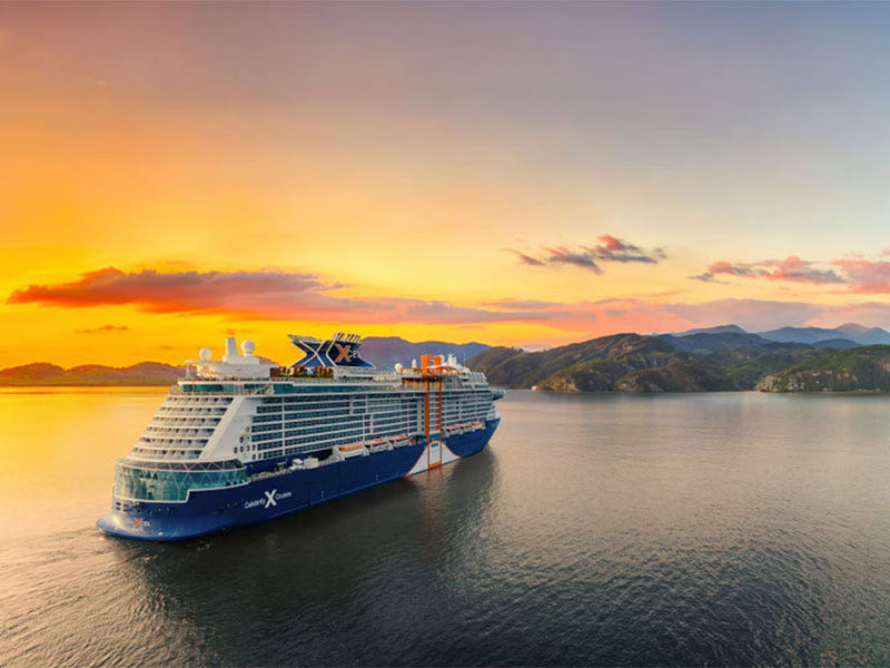 A sunset view of the Celebrity Xcel off the coast of a sunny location