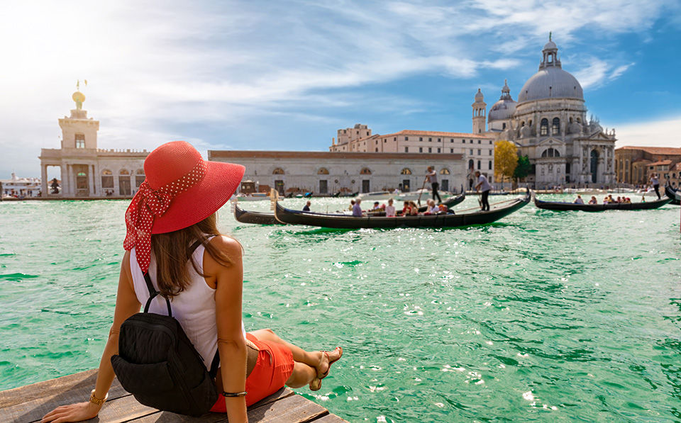 Attractive, female tourist enjoys the view to the Basilica di Santa Maria della Salute and Canale Grande in Venice, Italy