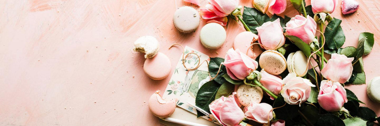 Flowers and macaroons laid out on a pink banner