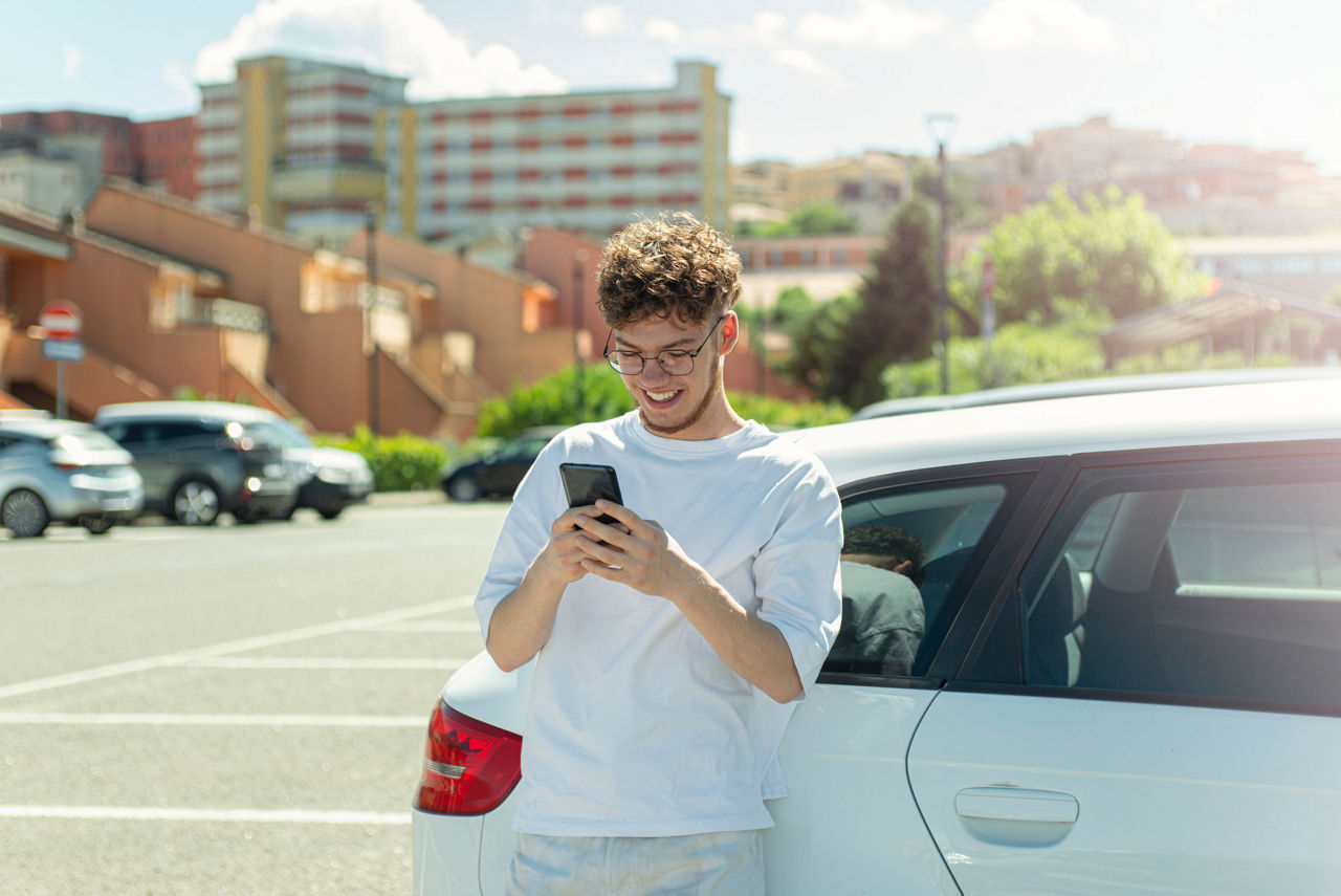 Young man using smartphone in a parking lot