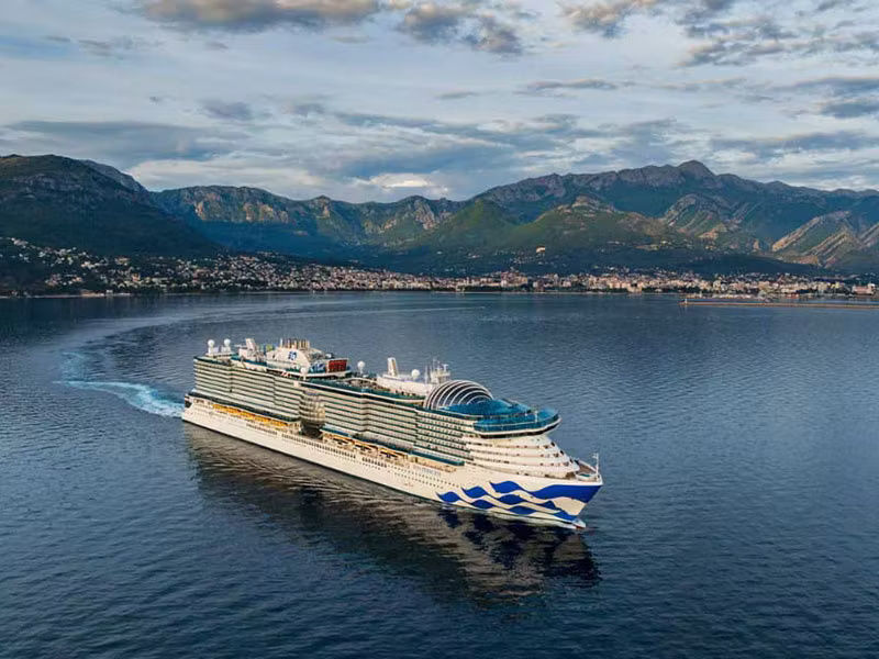 The Sun Princess cruise ship off the coast of a warm location with mountains