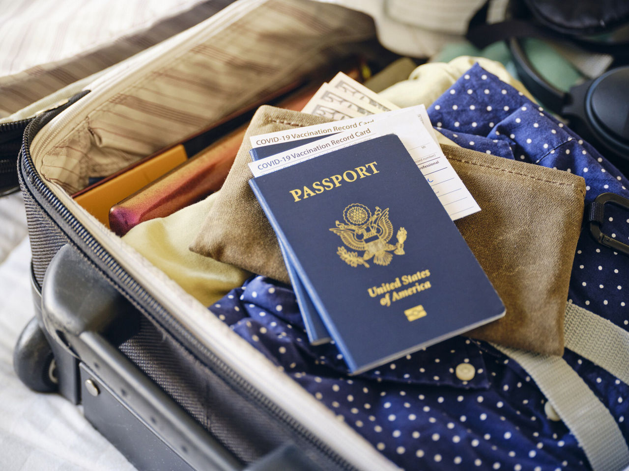 Passports laying on top of other items in an open suitcase.