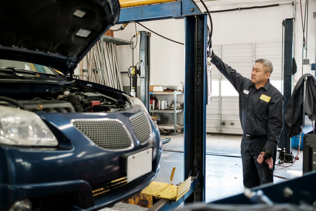 Mechanic using a lift to raise the car he is working on.