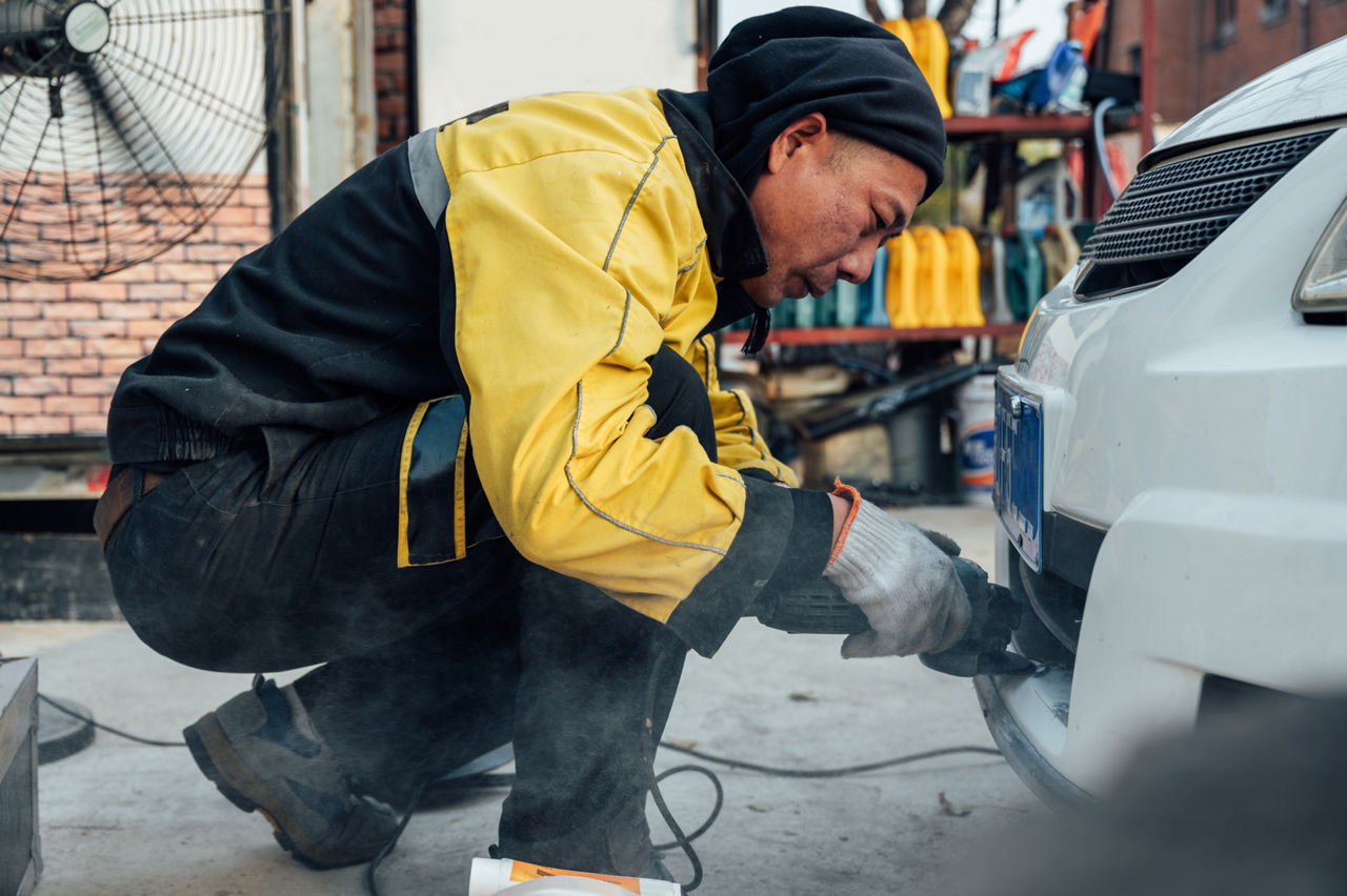 a mechanic drilling the front side of a car