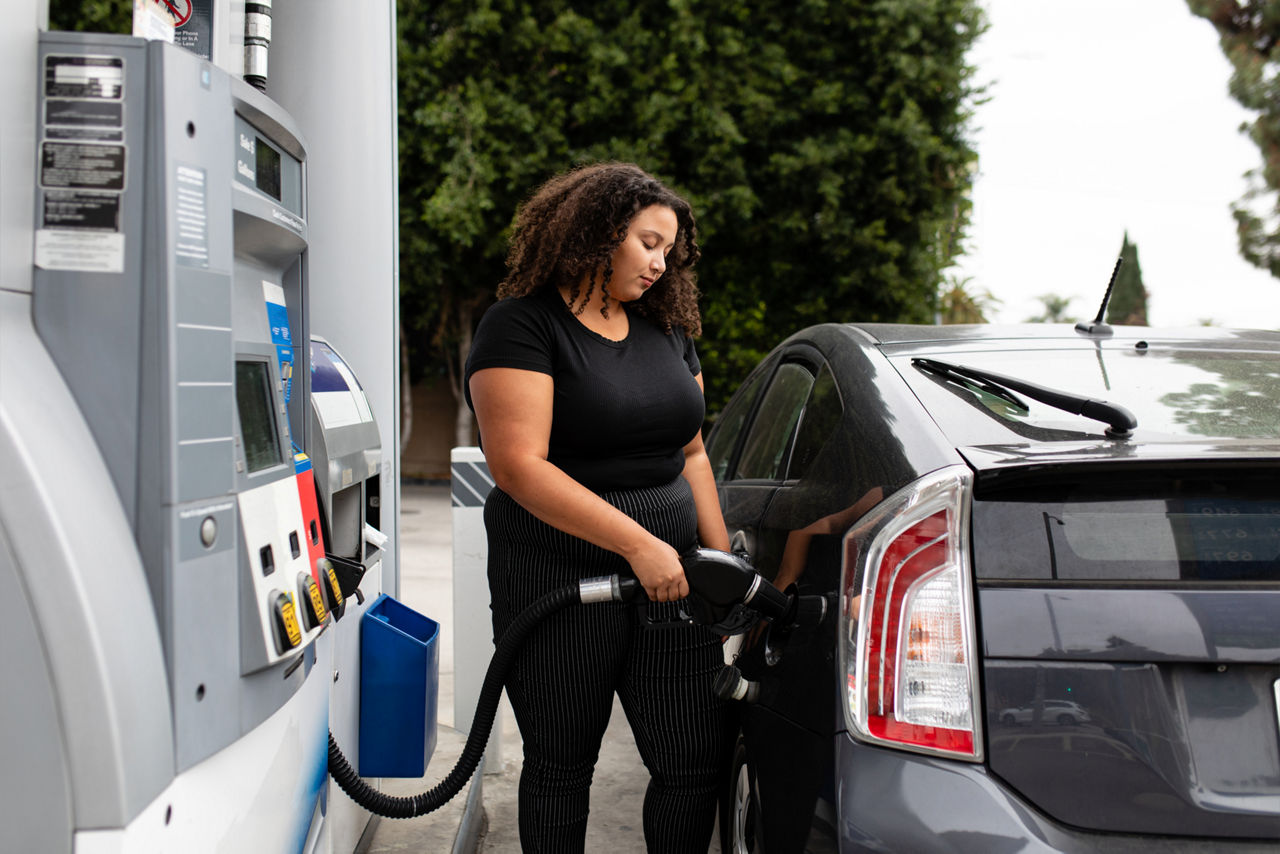 A woman in a gas station filling up her car with gas.
