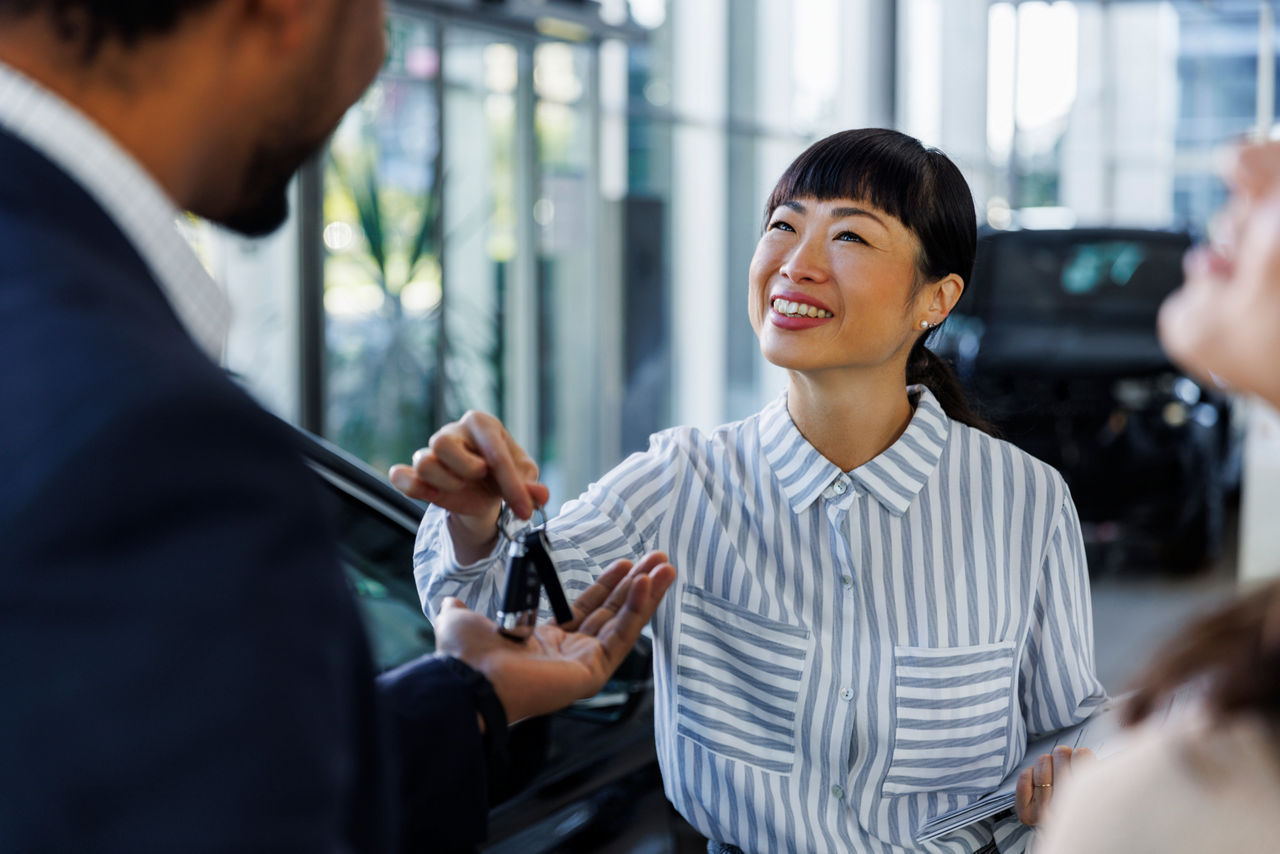  A woman handing over keys to a car to someone else.