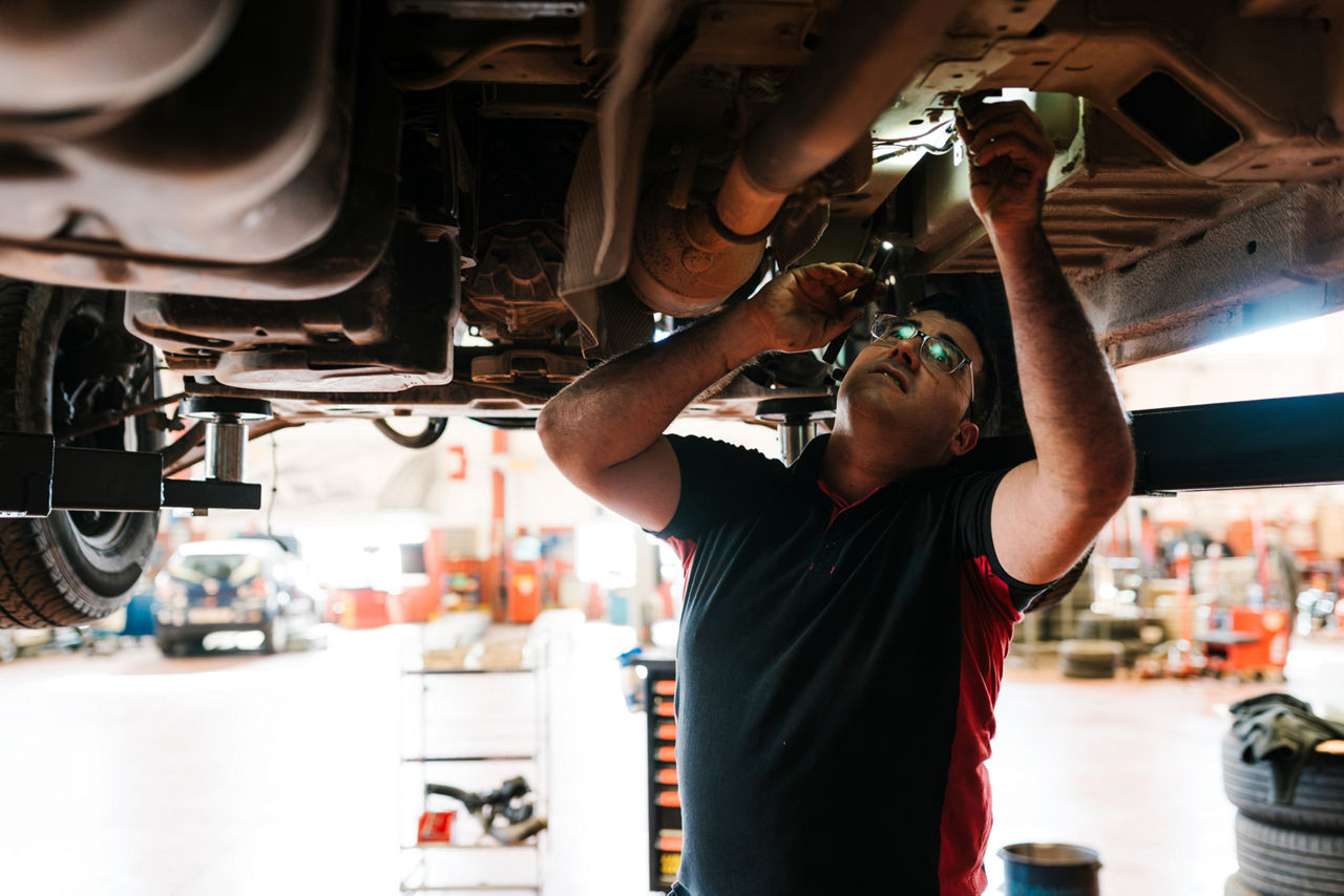 mechanic looking at the underside of his car