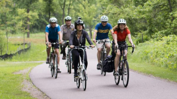 A group of people on bikes on a paved trail through a park.