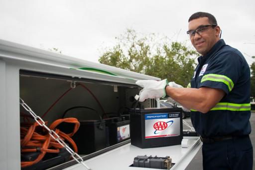 AAA technician unloading a car battery from tow truck