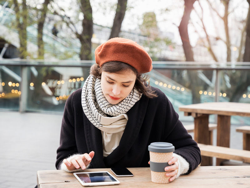 Woman reading her tablet in the cool outdoors dressed for winter