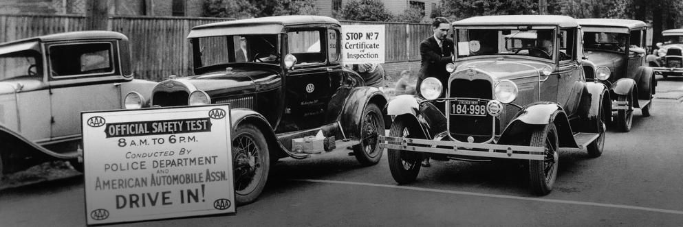 Historical photo of automobiles lined up for a safety inspection sponsored by local law enforcement and AAA