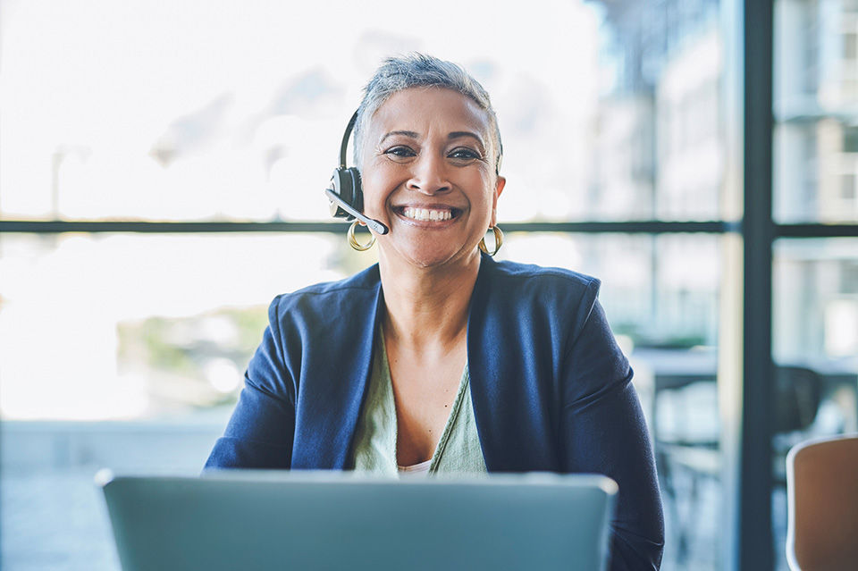 Smiling AAA Travel Agent with her headset and laptop