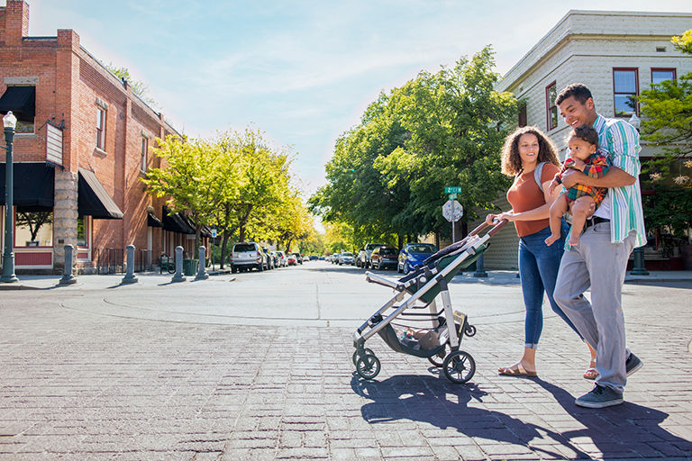 Family walking down the street with their child and stroller in hand.