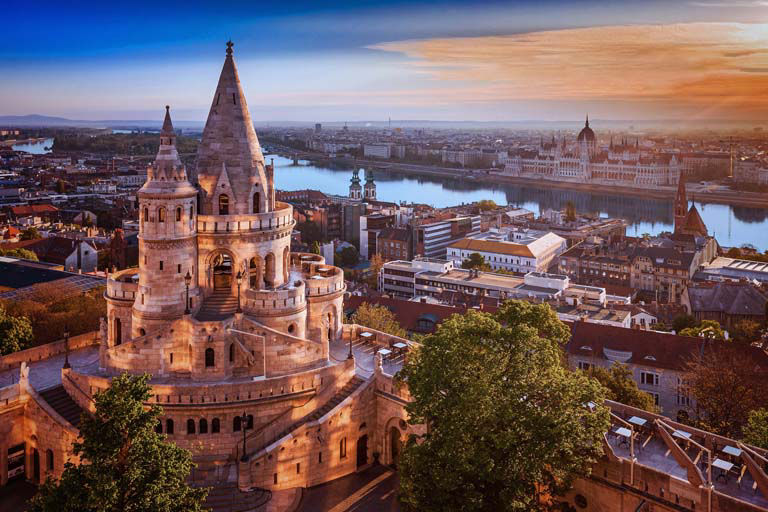 Panoramic view overlooking the Danube and the Budapest skyline at sunset.