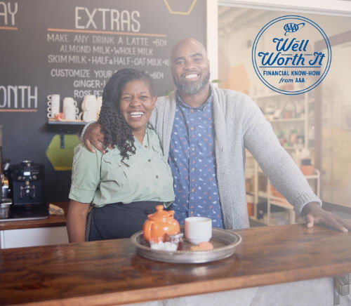 A couple stands at the counter of their store smiling. 