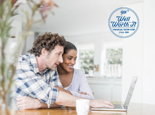 Couple sitting at table looking at laptop