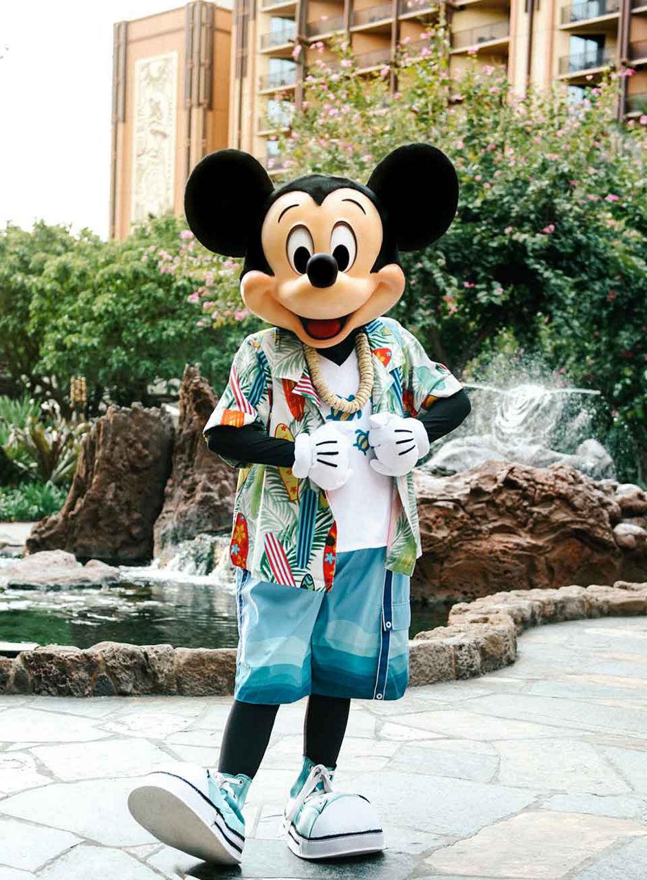 Mickey mouse at disney's aulani resort in hawaii smiling for the camera dressed in his hawaiian shirt.