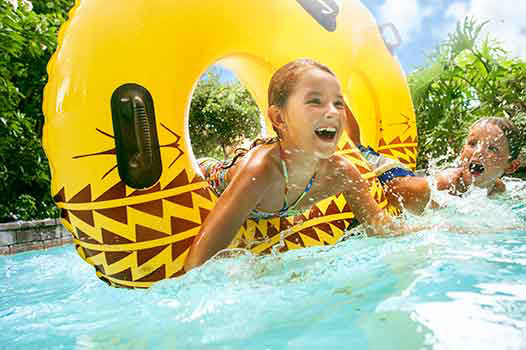 two kids swim in a lazy river at aulani resort.