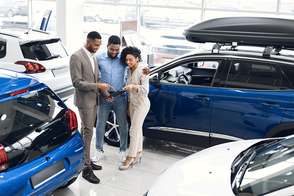 Couple Buying New Car Choosing Auto With Manager In Dealership.