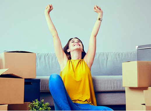 Woman surrounded by boxes happy to be in new home.
