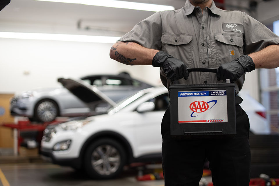 Mechanic holding a car battery.