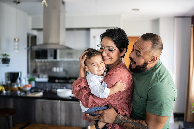 Family in their dining room, the mother is holding their young baby.