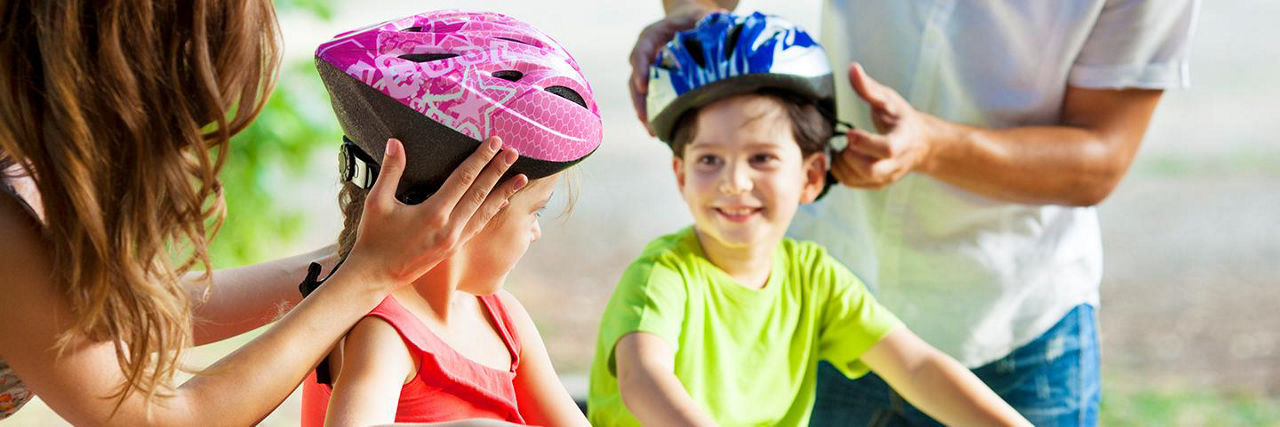 Parents putting safety bike helmets on kids