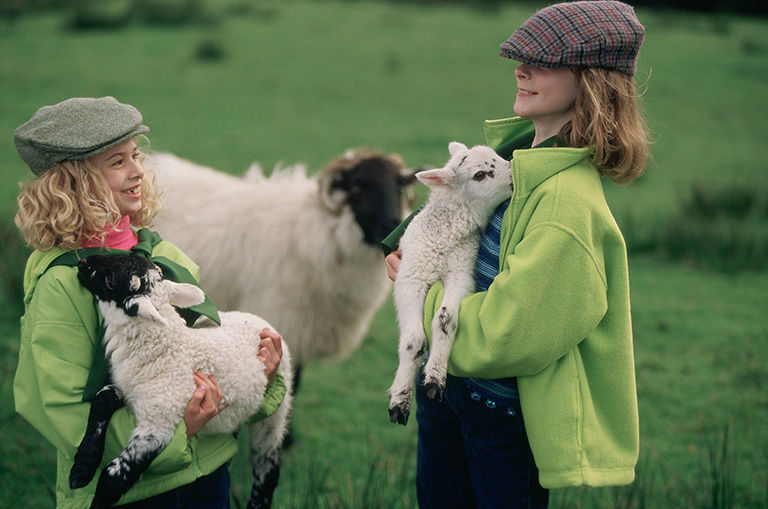 Children holding a sheep in the Scottish countryside.