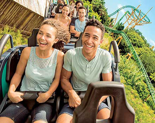 Couple sits in the front on a roller coaster ride smiling and laughing together.