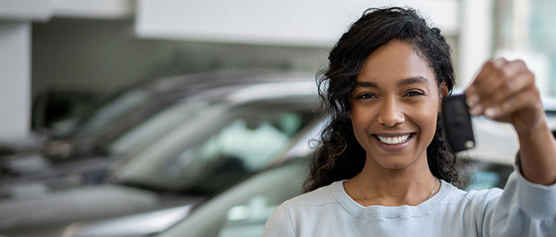 Women holds up key to her new car. 