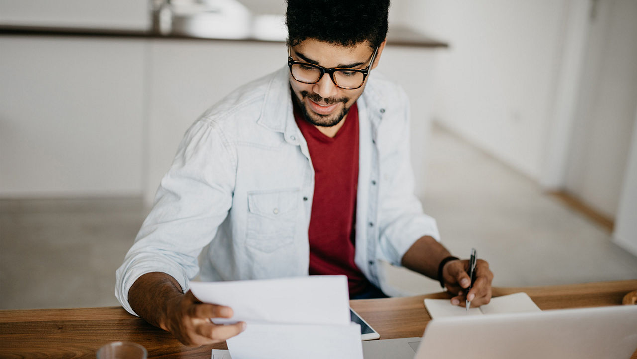 A man sitting at a desk reviewing paperwork.