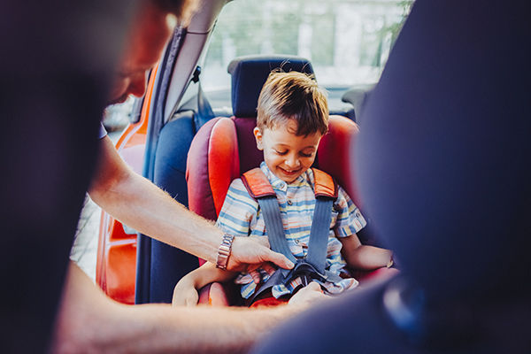 Caring father ensures his son’s safety by fastening his seatbelt in a car seat after picking him up from school.