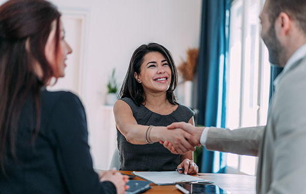 Businesspeople handshaking across the table during a meeting in modern office. Group of business persons in business meeting. Shot of three entrepreneurs on meeting in board room. Creative business team on meeting in the office.