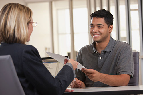 A man is handing a women his resume to read. 