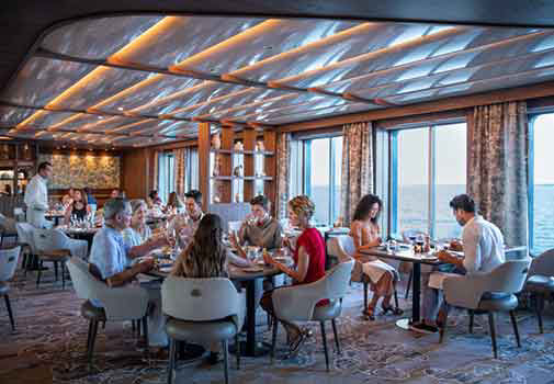Group of people dining on board of one of the celebrity cruise ships looking out to the ocean view.